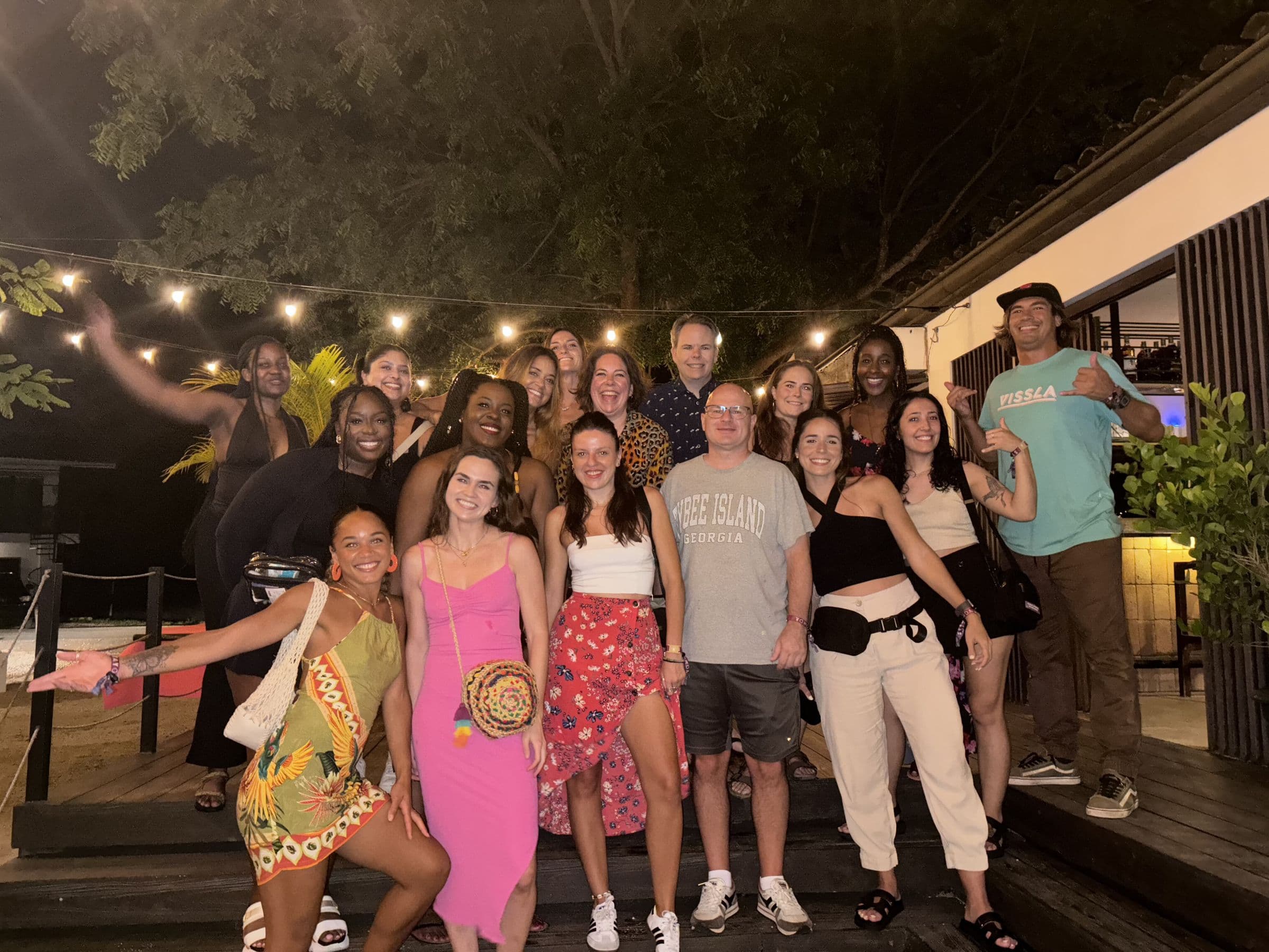 Full cohort under string lights for a farewell dinner