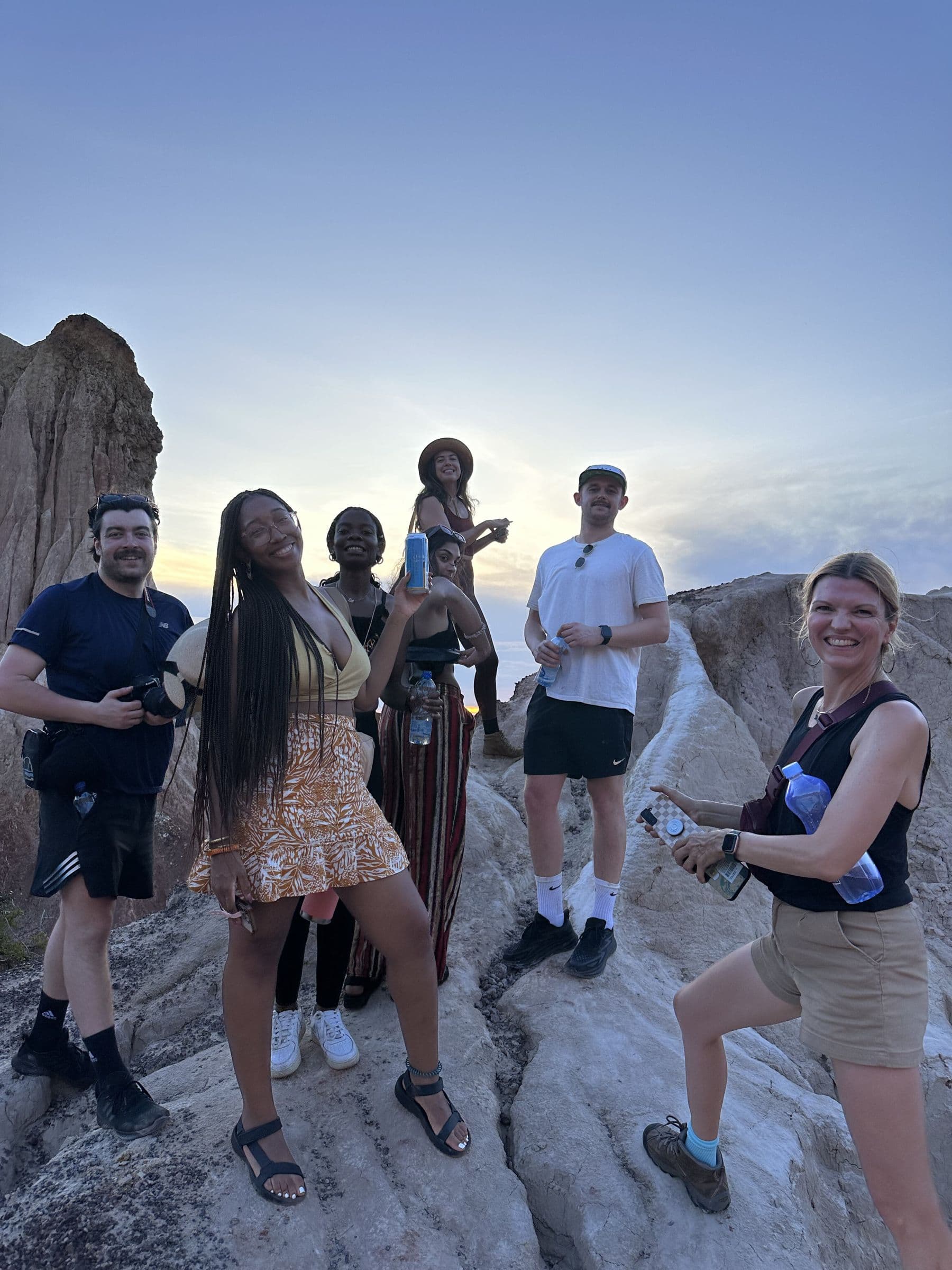 Group posing on rocky cliffs at sunset